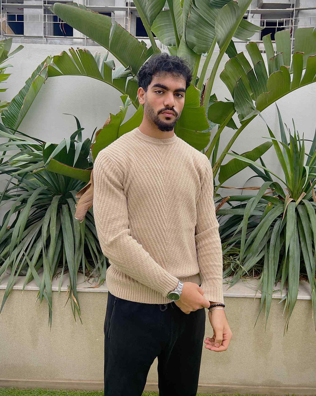 Man wearing a beige sweater and dark pants 