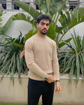 Man wearing a beige sweater and dark pants 