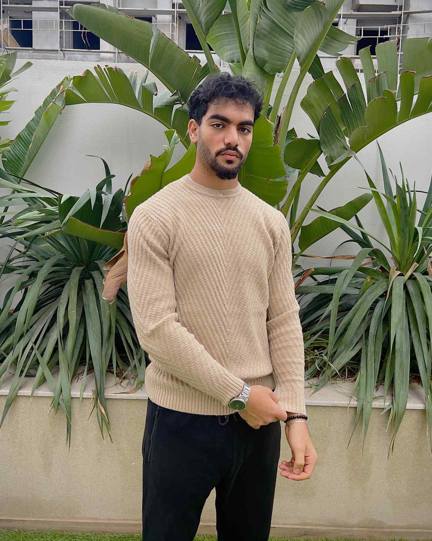Man wearing a beige sweater and dark pants 
