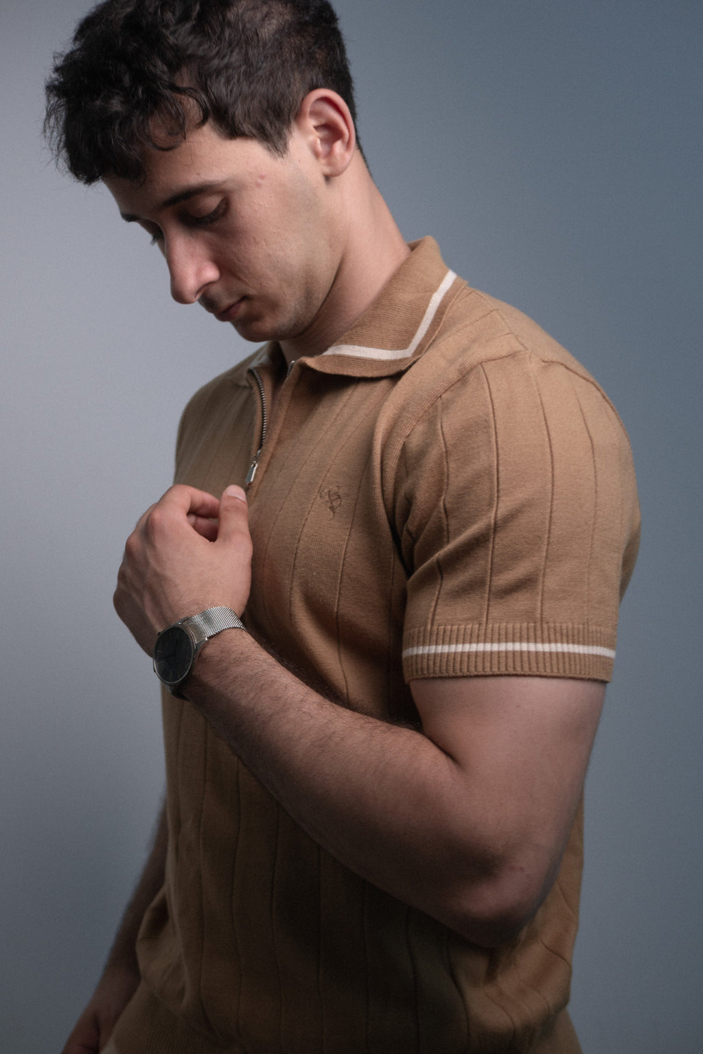 Man wearing a brown polo shirt against a gray background