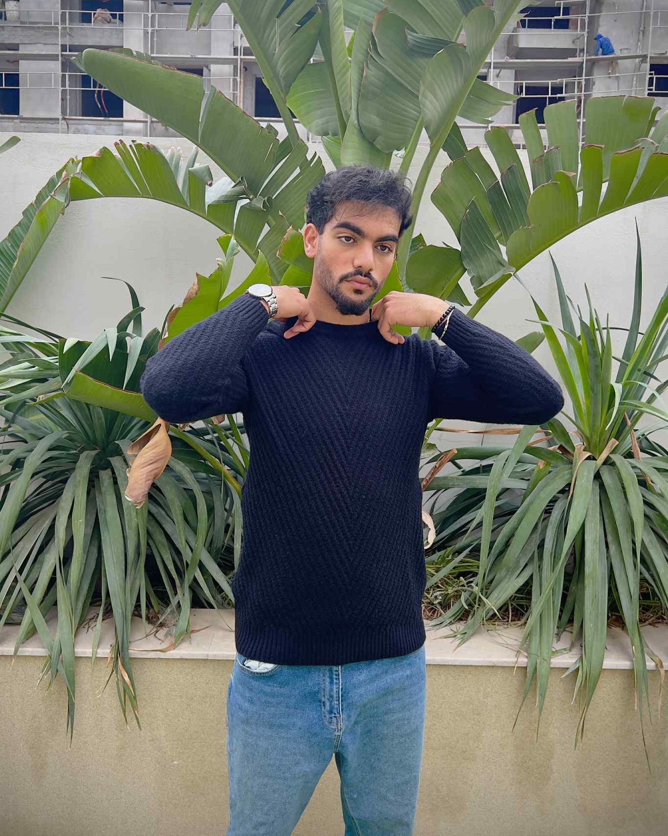 Man wearing a black sweater and light blue jeans 
