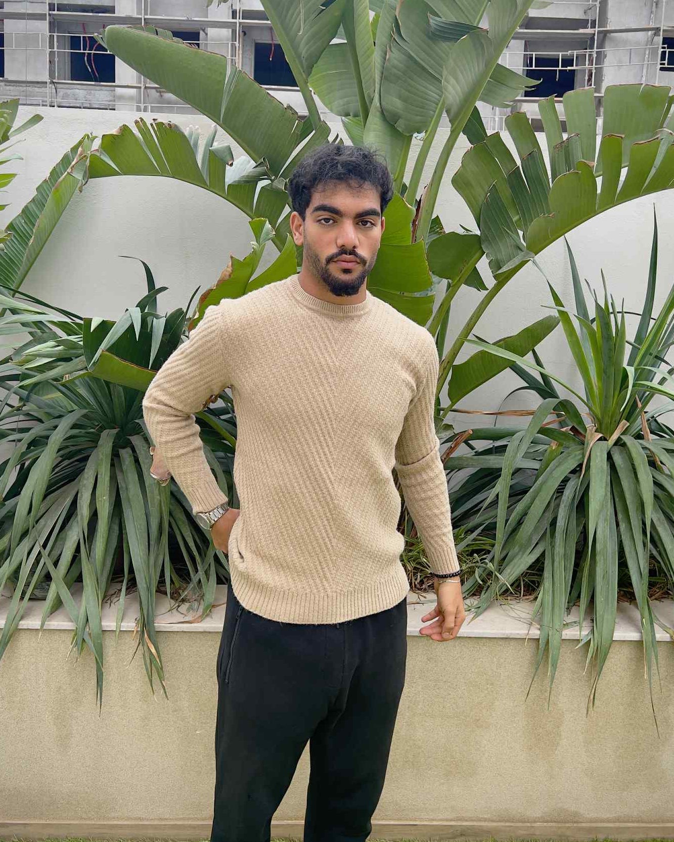 Man wearing a beige sweater and dark pants 