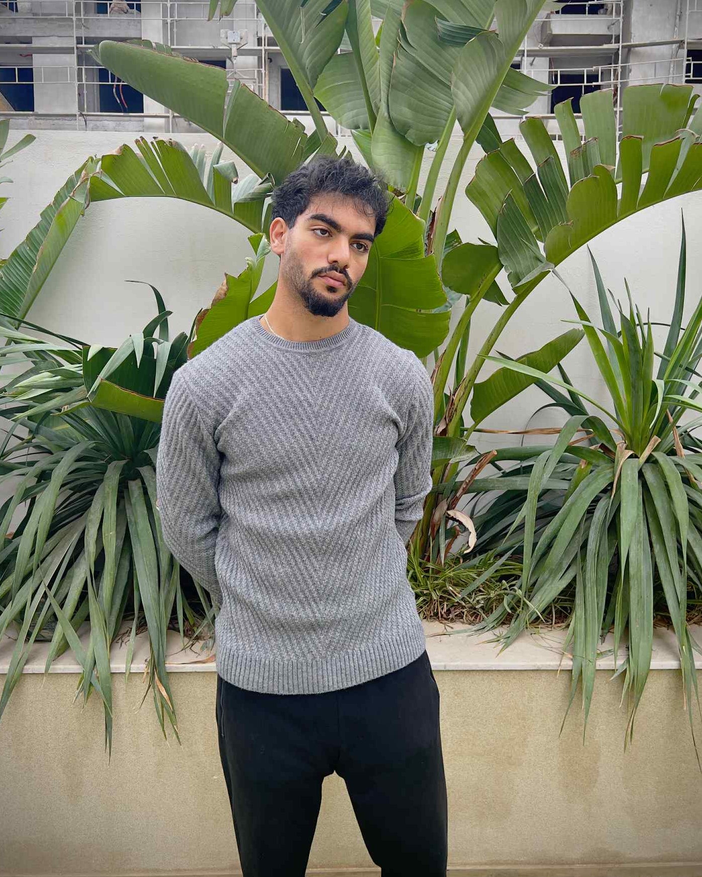 Man wearing a grey sweater and dark pants 